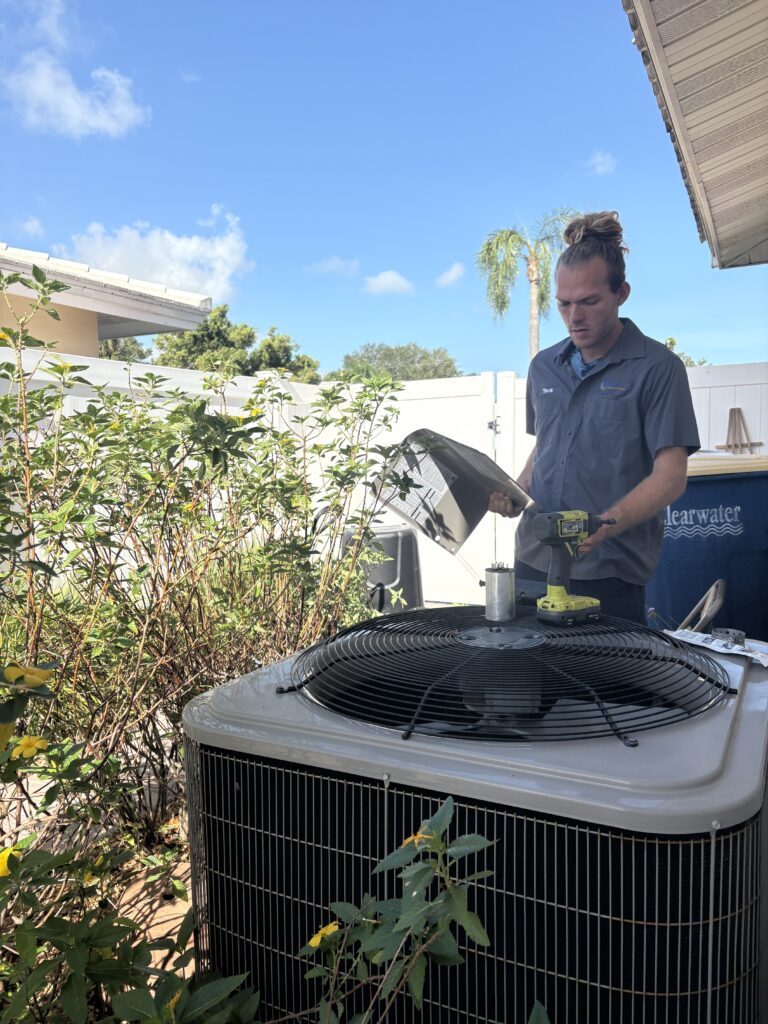 Technician inspecting outdoor air conditioning unit for efficiency and cleaning.