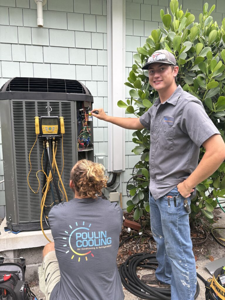 Technicians inspecting and cleaning an outdoor air conditioning condenser unit.