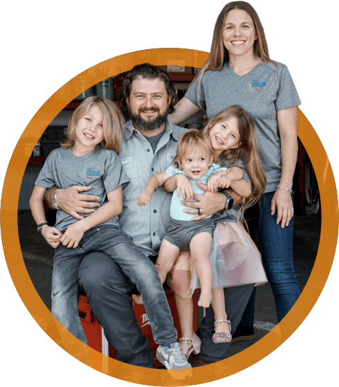 Poulin Cooling family portrait featuring a smiling father with three children and a mother, all wearing branded shirts, set against a backdrop of a service garage, emphasizing the family-oriented nature of the local AC repair business in Palm Harbor, FL.