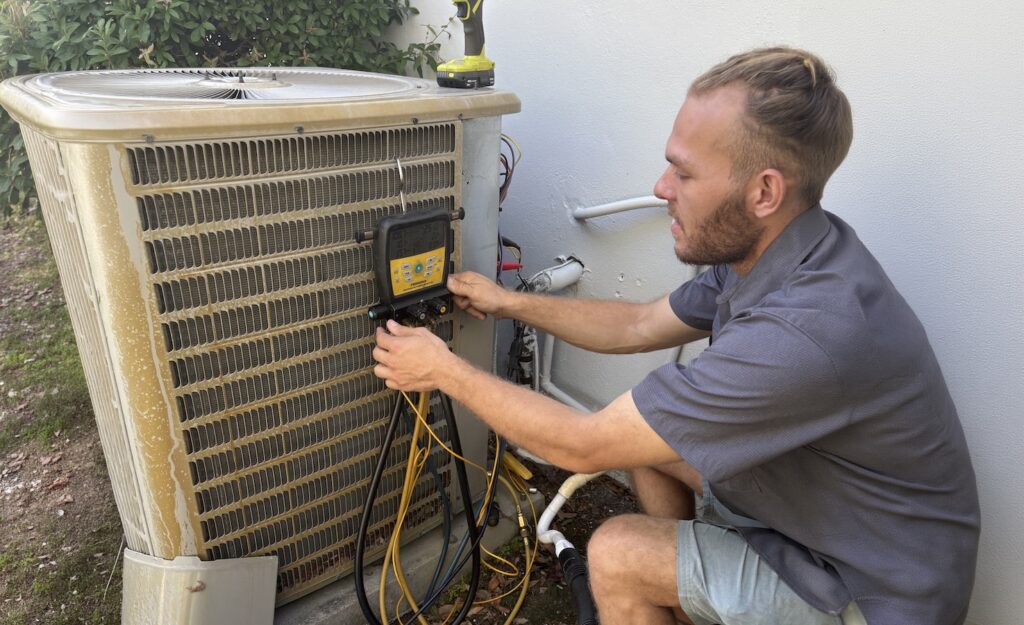 Technician inspecting and repairing an outdoor air conditioning unit.