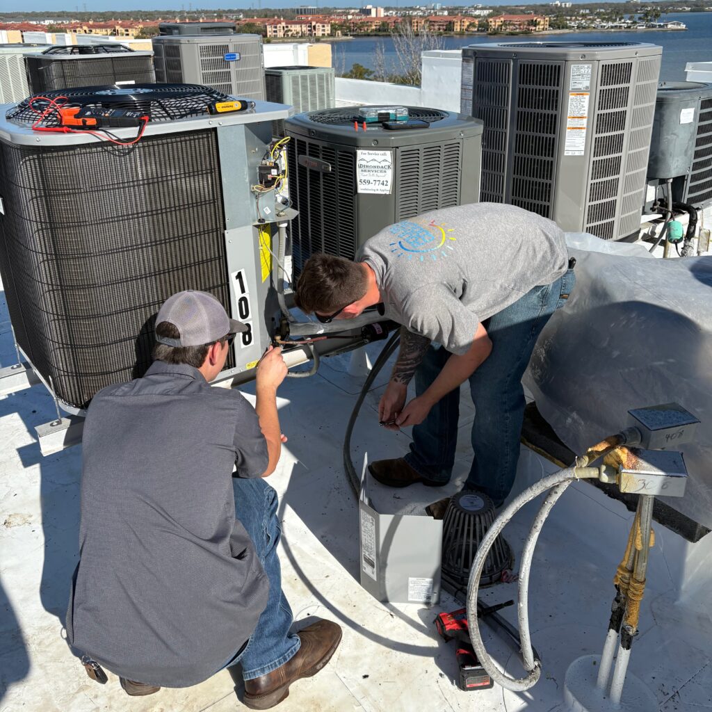 HVAC technicians servicing rooftop air conditioning units for optimal performance.